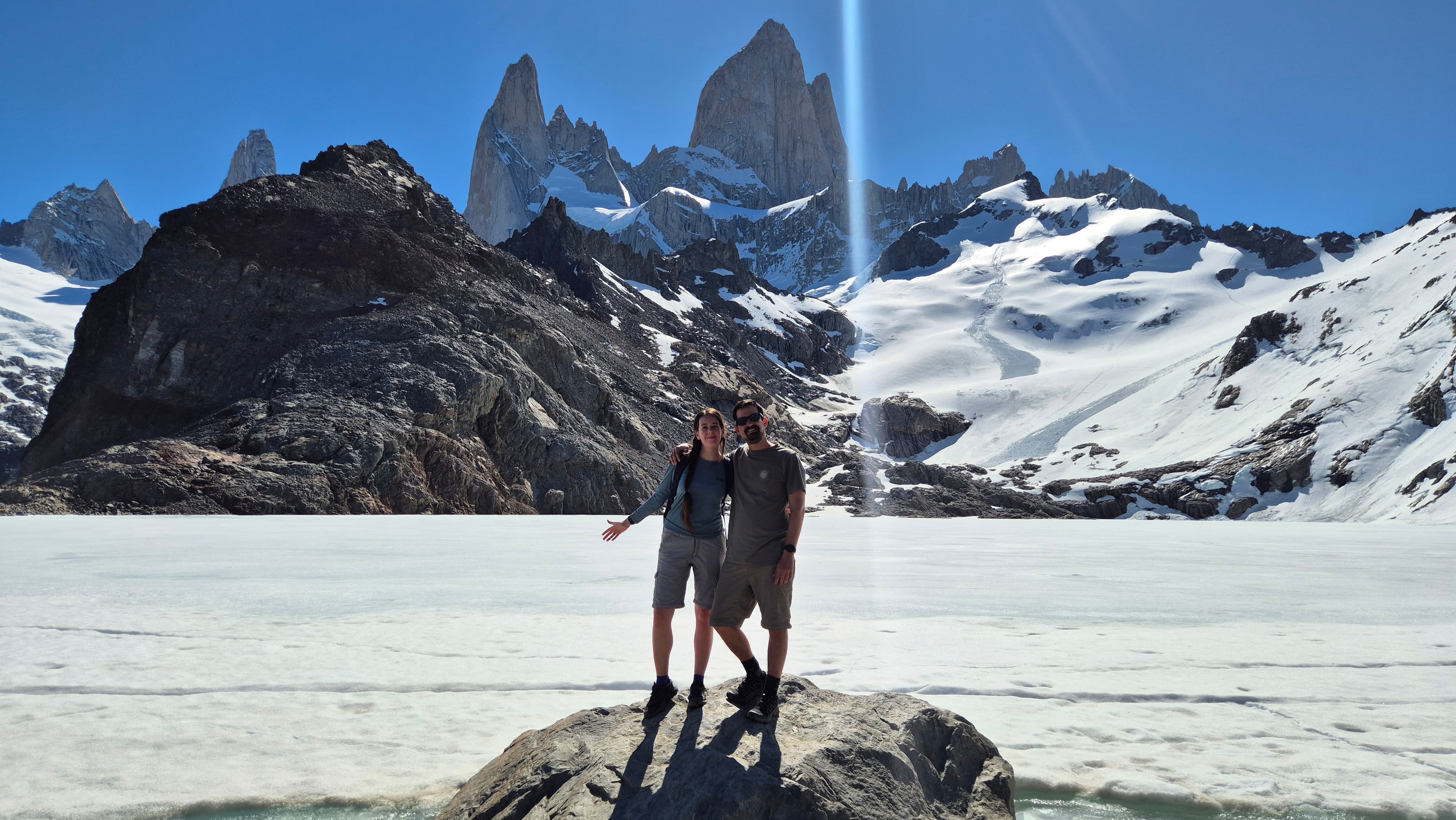 Clari y Fede juntos frente a una laguna y montañas nevadas